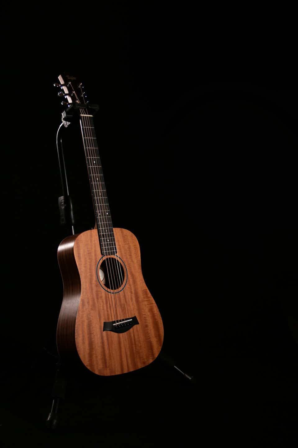 Eine Akustikgitarre steht auf einem schwarzen Studio-Ständer.